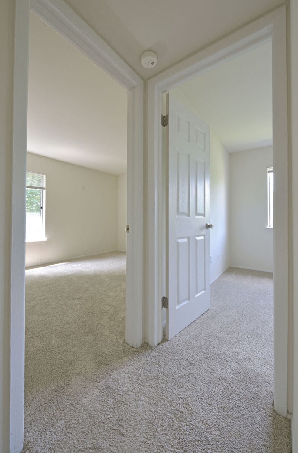 an empty bedroom with a white door and carpet at Sycamore Creek Apartments, Lake Orion, MI