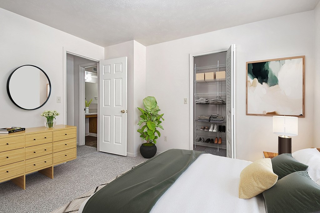 A bedroom with a bed, dresser, and a walk-in closet at Tall Oaks Apartment Homes, Michigan, 49009