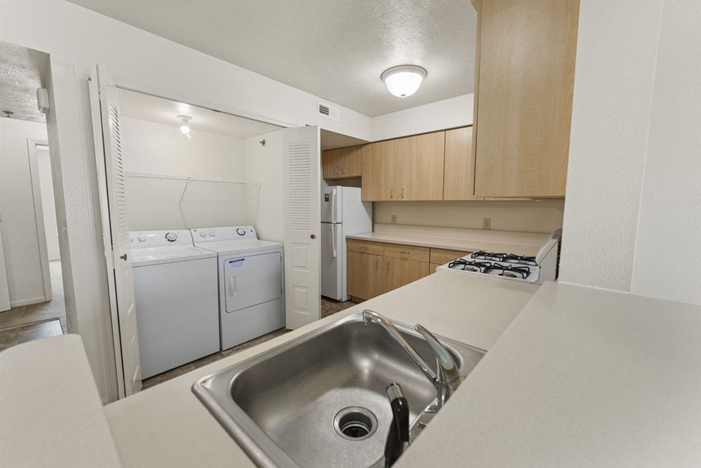 A kitchen with a sink, stove, and a washer and dryer at Tall Oaks Apartment Homes, Michigan, 49009