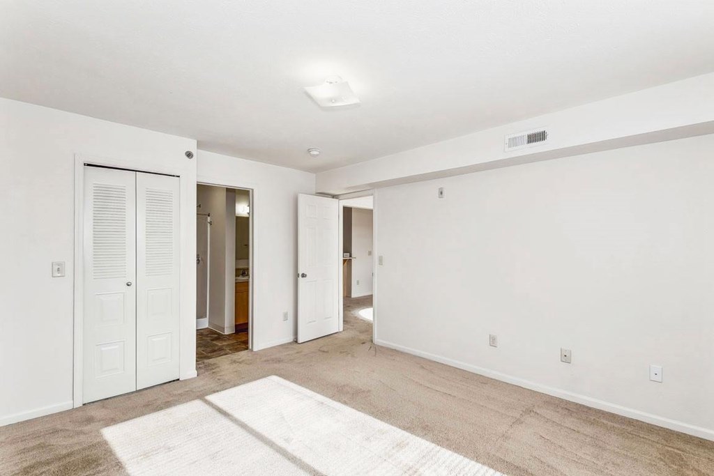 A spacious bedroom with an ensuite and a door to a walk-in closet at Tall Oaks Apartment Homes, Kalamazoo, MI, 49009