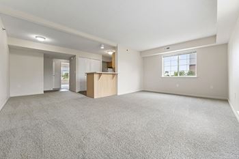 A kitchen with white appliances and an enlarged living room at Tall Oaks Apartment Homes, Kalamazoo, MI, 49009