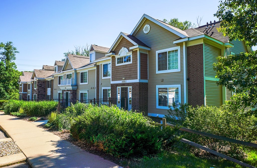 An exterior apartment building with green bushes in front at Tall Oaks Apartment Homes, Kalamazoo, MI, 49009