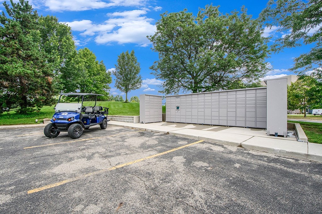 A blue golf cart is parked next to Amazon Hub package lockers at The Crossings Apartments in Grand Rapids, MI
