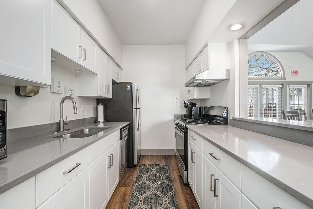 A clubhouse kitchen with white cabinets and stainless steel appliances at The Crossings Apartments in Grand Rapids, MI