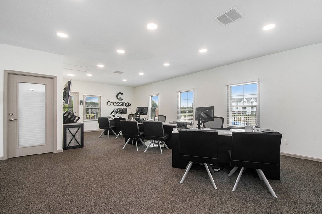 A leasing office with a carpeted floor and desks with chairs at The Crossings Apartments in Grand Rapids, MI