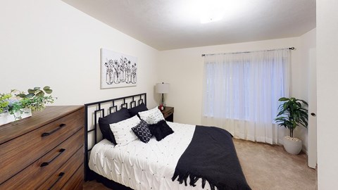 A bedroom with a bed, nightstand, and a potted plant at Tracy Creek Apartment Homes in Perrysburg, OH
