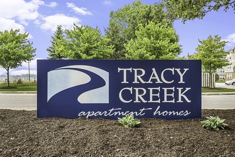 A sign for Tracy Creek Apartment Homes is displayed in front of a building.