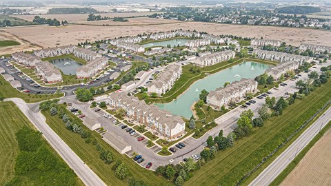 A bird's eye view of a residential area with a pond and apartment buildings at Tracy Creek Apartments, Perrysburg