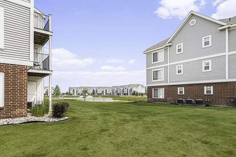A grassy area with a pond behind apartment buildings at Tracy Creek Apartments, Perrysburg