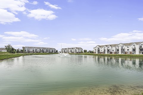 A large body of water with a fountain in the middle and apartment buildings in the background at Tracy Creek Apartments, Perrysburg