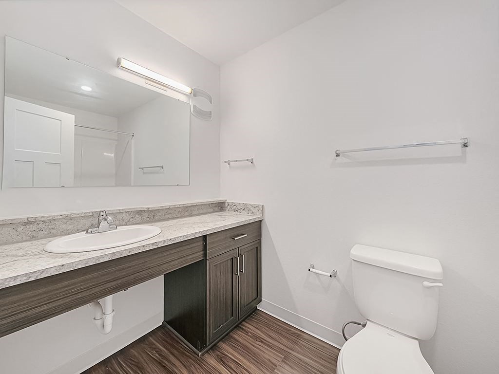 A white toilet sits in a bathroom next to a sink and mirror