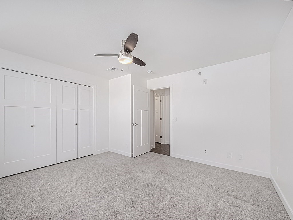 A room with a ceiling fan and carpeted floor