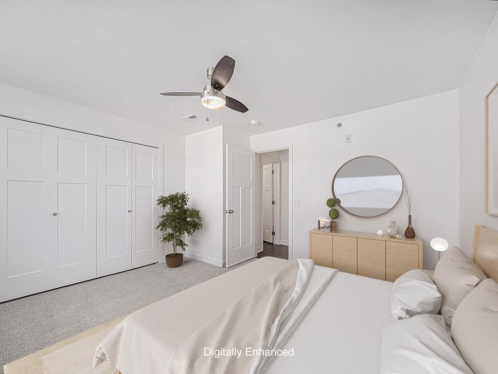 A bedroom with a bed, dresser, mirror, and a ceiling fan at Trade Winds Apartment Homes, Elkhorn, Nebraska