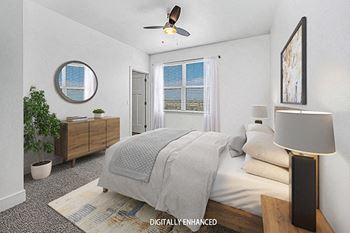 A bedroom with a bed, a ceiling fan, and a potted plant at Trade Winds Apartment Homes in Elkhorn, NE