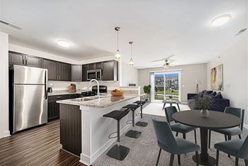 A modern kitchen with a breakfast bar and dining table and chairs at Trade Winds Apartment Homes, Elkhorn, NE