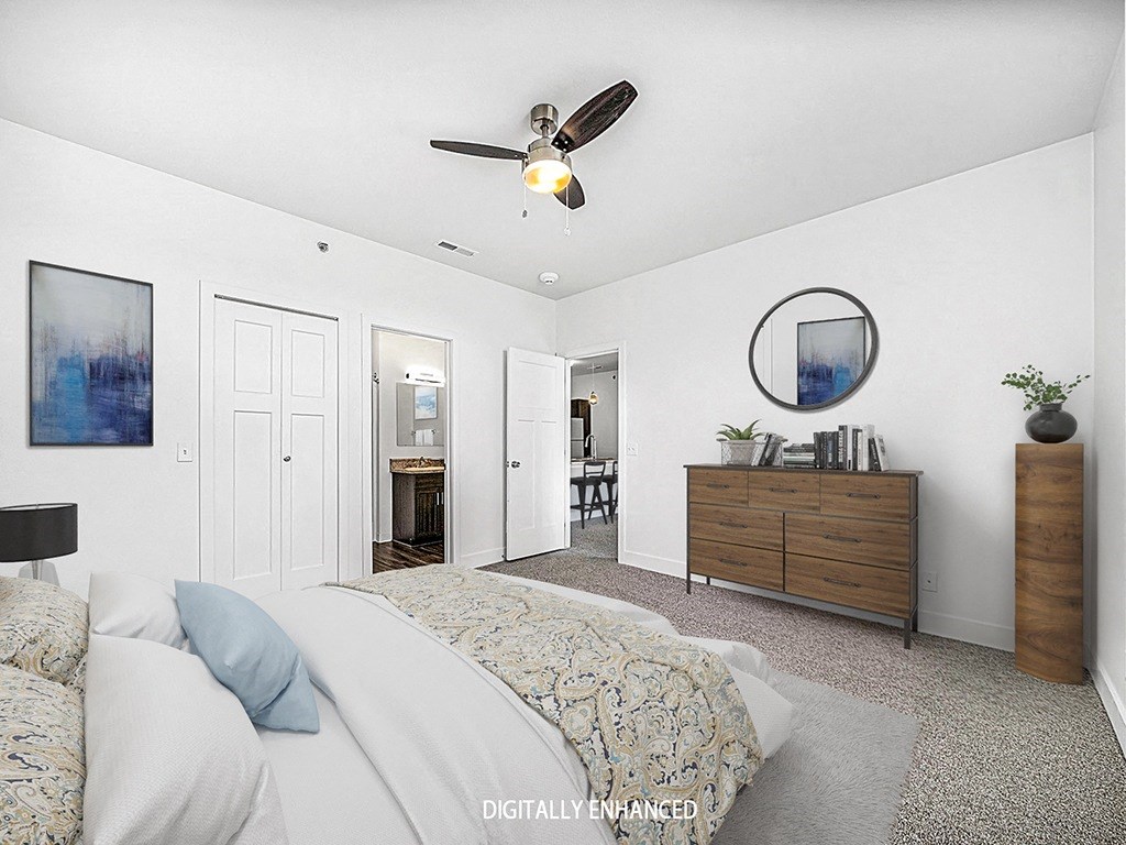 A bedroom with an ensuite, a bed, dresser, and ceiling fan at Trade Winds Apartment Homes, Elkhorn, Nebraska