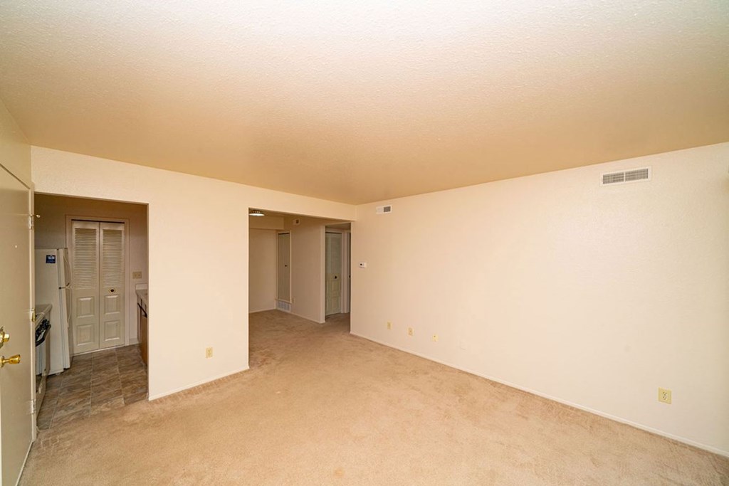 Empty living and dining room with a carpeted floor at Trappers Cove Apartments, Lansing