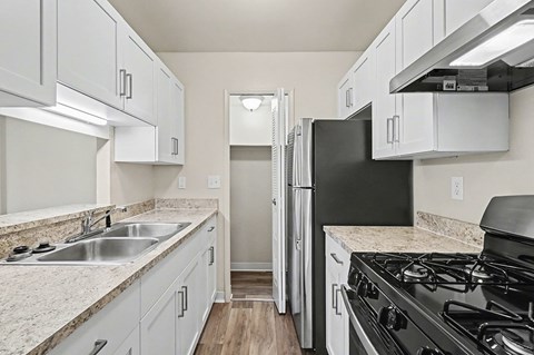 A kitchen with a black refrigerator and stove top oven.
