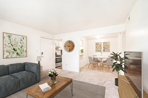 A living room with a grey couch, a wooden coffee table, and a round mirror on the wall.