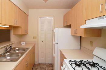 Galley Kitchen with Gas Range at Trappers Cove Apartments in Lansing, MI