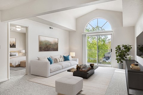 A living room with a large window and a painting on the wall.