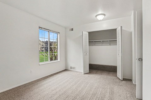 A room with a large window and a closet.
