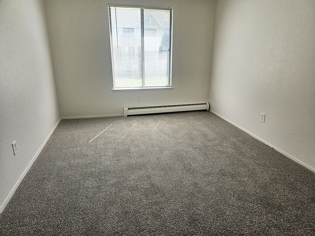 A room with a window and a radiator on the floor.