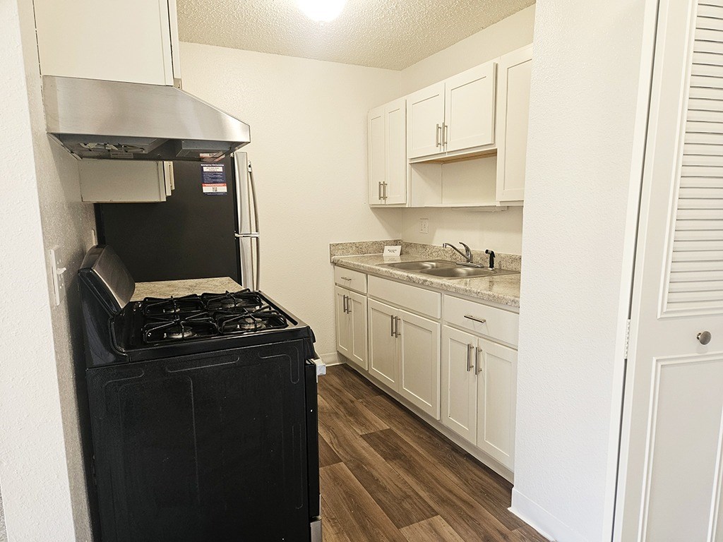 A black stove in a kitchen with white cabinets.