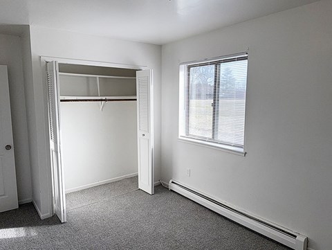 A white bedroom with a large closet and a window.
