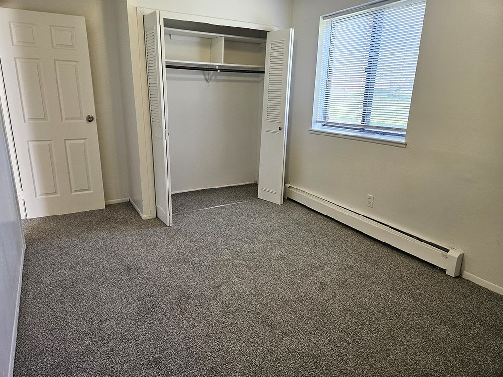 A bedroom with a closet and a large window at Waverly Park Apartments, Lansing