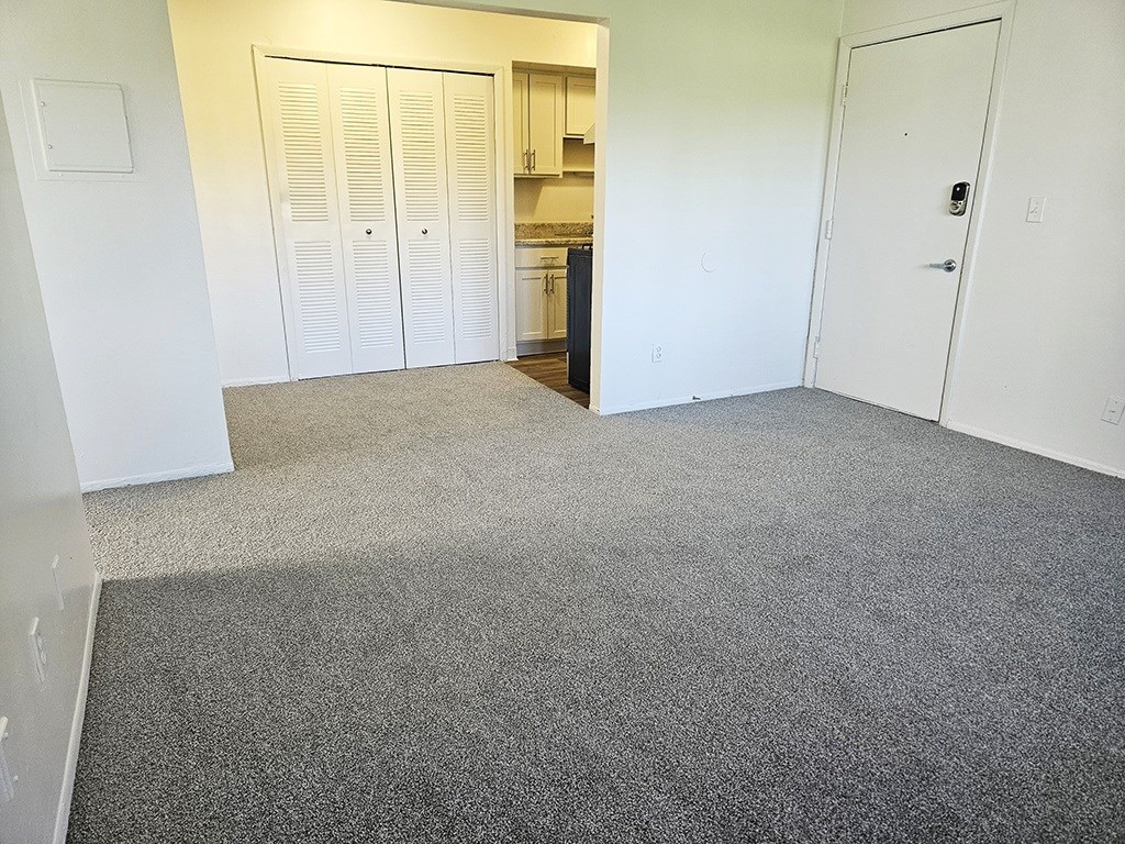 A dining room with a carpeted floor and a closet at Waverly Park Apartments, Lansing