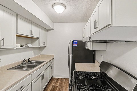 A kitchen with white cabinets and a black refrigerator.