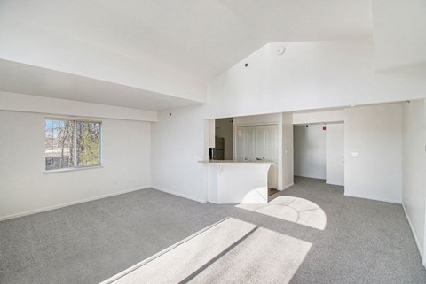 A spacious living room with a cathedral ceiling and a window at West Hampton Park Apartments in Elkhorn, NE 68022