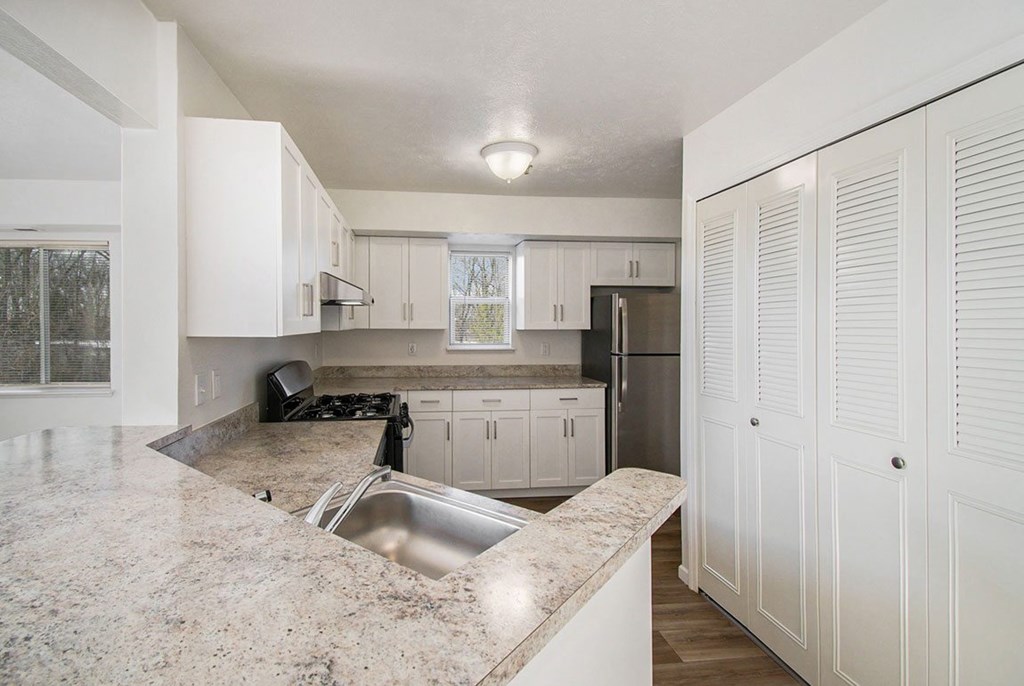A kitchen with a breakfast bar and white cabinets at West Hampton Park Apartments in Elkhorn, NE 68022
