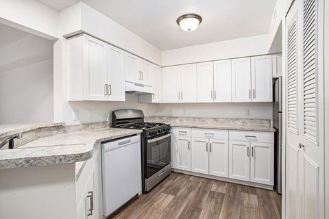 A kitchen with white cabinets and a marble countertop.
