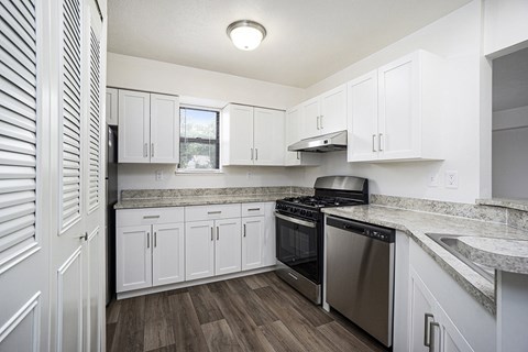 A kitchen with white cabinets and a stainless steel dishwasher and oven at Windmill Lakes Apartments, Holland, Michigan 49424
