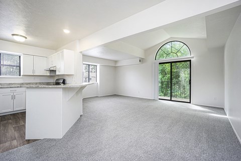 A spacious, end style living room with a kitchen area and a large window at Windmill Lakes Apartments, Holland, Michigan 49424