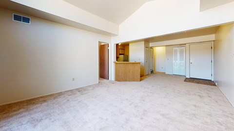 A spacious living and dining room with a carpeted floor and a breakfast bar at Windmill Lakes Apartments, Holland, MI