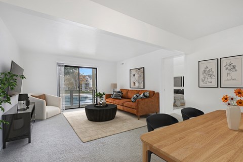 A living room with a brown sofa and a sliding glass door to a balcony at Windmill Lakes Apartments, Holland, Michigan 49424