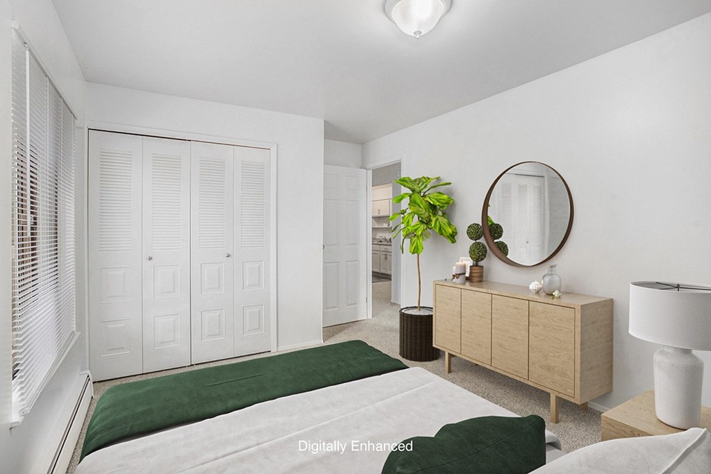 An upgraded bedroom with a green bedspread and a large closet at Wingate Apartments, Michigan