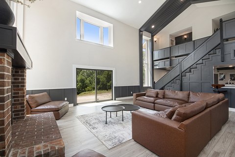 A living room with a brown couch and a brick fireplace.