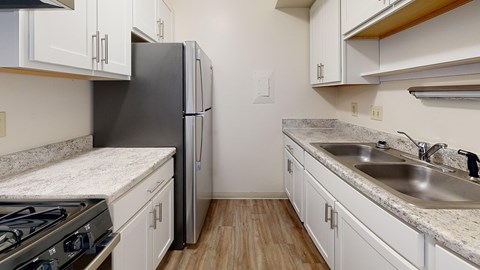A kitchen with a black refrigerator and a stove top oven.