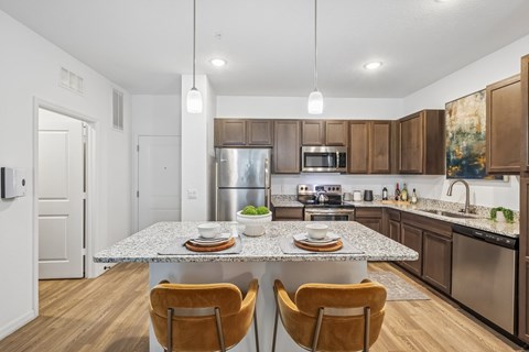 A modern kitchen with a granite countertop and stainless steel appliances.