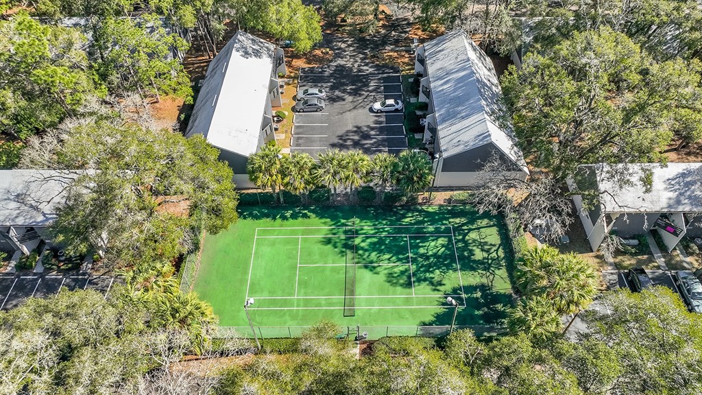 a tennis court in the middle of a backyard surrounded by trees