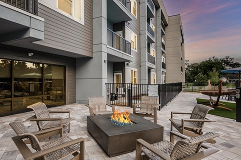 A patio with chairs and a fire pit in front of a building.