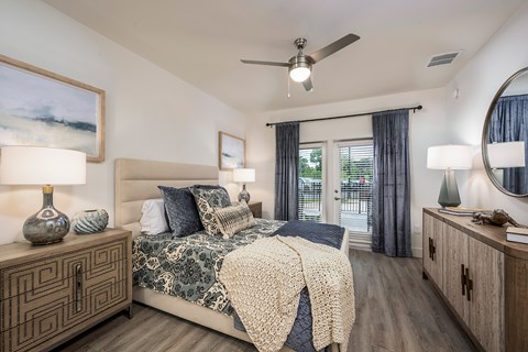 A bedroom with a bed, nightstands, and a ceiling fan.