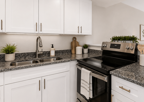 A modern kitchen with white cabinets and a black stove top oven.