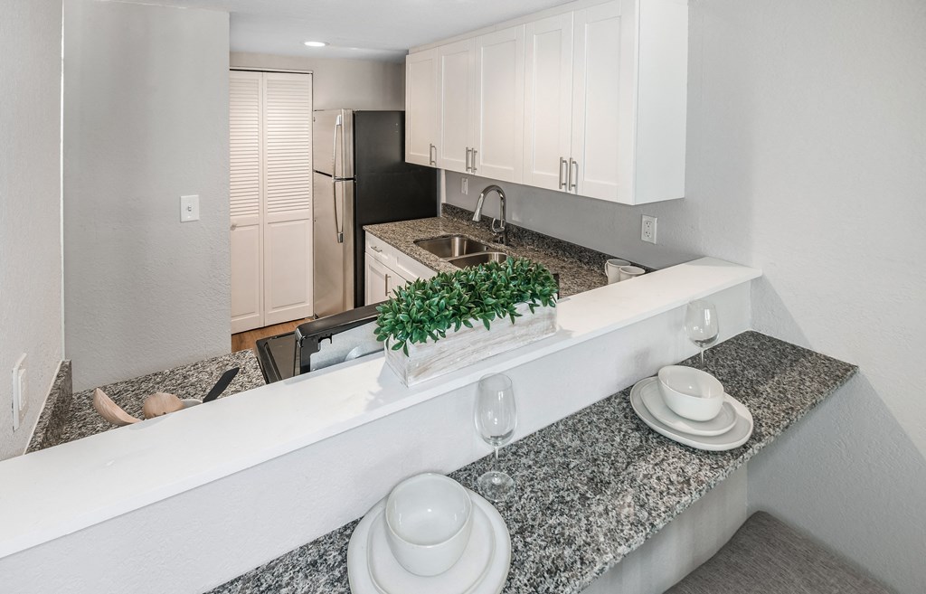 a kitchen with granite counter tops and white cabinets