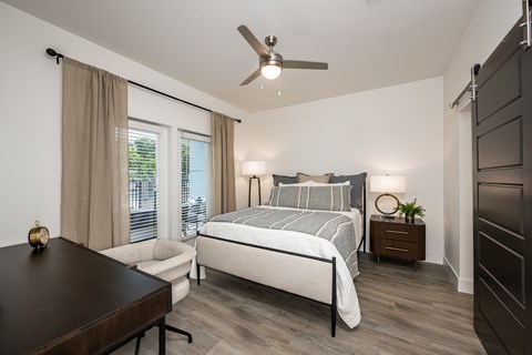 A bedroom with a large bed, a chair, and a ceiling fan.