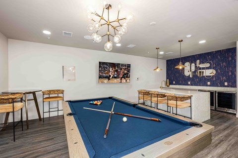 A pool table with a blue cloth and a cue stick on it.